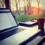 using a laptop while having a cup of coffee 