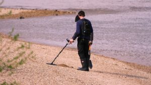 men using a metal detector in a beach